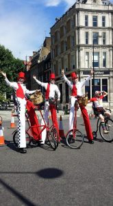 Checkered Cyclist Stilt Walkers for hire. Our comedy stilt walkers are available to book for family fun days in London & the UK.