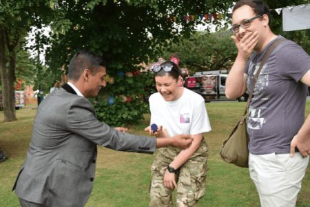 Close-up magician performing in front of a crowd at an event in the UK.