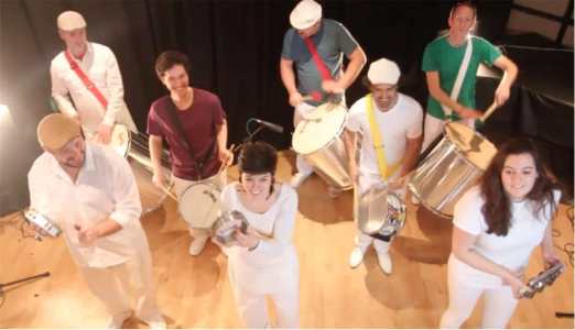 Our drumming troupe for hire is a talented group of samba drummers who will provide a lively and up-tempo time for all at your next event. This samba drumming troupe are incredibly versatile and can offer anything from 3, 6, 12 right up to 50 samba drummers for any event. These internationally-renowned samba drummers have performed across the world, bringing their Brazilian-themed magic with them. This drumming troupe is a sure-fire way to get everyone up and dancing at your event.   Our carnival drummers will be sure to create an exciting Rio Carnival atmosphere at your next event.  These talented carnival drummers will transport you to the beaches of Copa Cabana and the streets of Rio with their intoxicating rhythms and beats. Our carnival drummers are also perfect for sports-themed events or half-time shows. What better way to get the crowd going than with these loud and exciting carnival drummers.     This samba drumming troupe features a variety of drummers and percussionists who are all incredibly passionate about creating an authentic Rio-themed experience for your event. As demonstrated in the video, our samba drummers can demonstrate a number of different techniques including the “call and response”. These talented carnival drummers have performed as a drumming troupe at a diverse range of events which makes them perfect for a wide range of events.   This samba drumming troupe are incredibly popular for all types of events but especially for marketing and experiential events. The samba drumming show is the perfect display to captivate and instantly grab people’s attention. To date, our carnival drummers have performed at marketing campaigns for companies such as; Pandora, Corona, American Express and much more. Samba drumming troupes are the perfect entertainment option to hire for marketing campaigns because they will create an unforgettable experience for all. Our drumming troupe will also ensure that a high-energy and electrifying atmosphere is created with their music. These vibrant carnival drummers will be sure to keep guests and clients captivated at your next event.  Our talented samba drumming troupe can also be hired specifically for team building events. Samba drumming is a fun-filled way to get everyone engaging with each other. With fun games like “call and response”, our carnival drummers will be sure to create a binding team building time for all.  Our samba drummers are a fun-filled carnival drummer entertainment option that will be sure to bring joy and create the perfect experience for everyone at your next event. The samba band are the perfect drumming troupe to hire for a wide range of events including; corporate events, sports-themed events or brand activations in the UK and across the world.