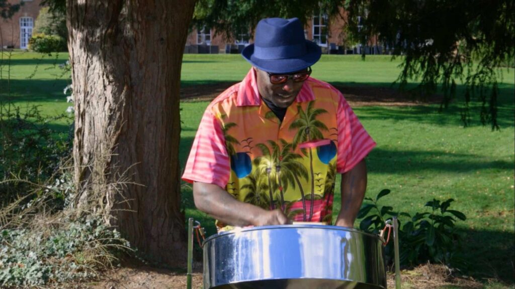 A colourful steel drummer in pink Caribbean themed top playing the steel drums