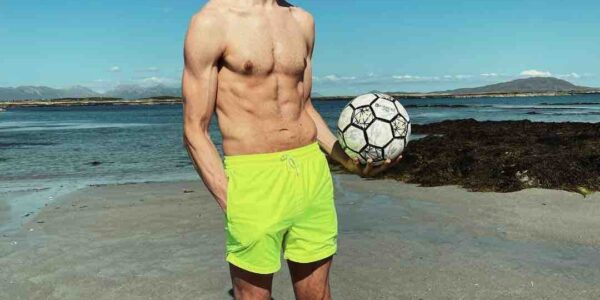 Football-Freestyler-Holds-Football-On-Beach
