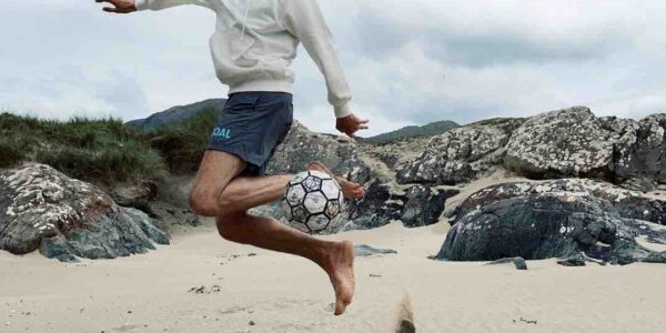 Freestyling-Football-Player-Kicks-Ball-On-Beach