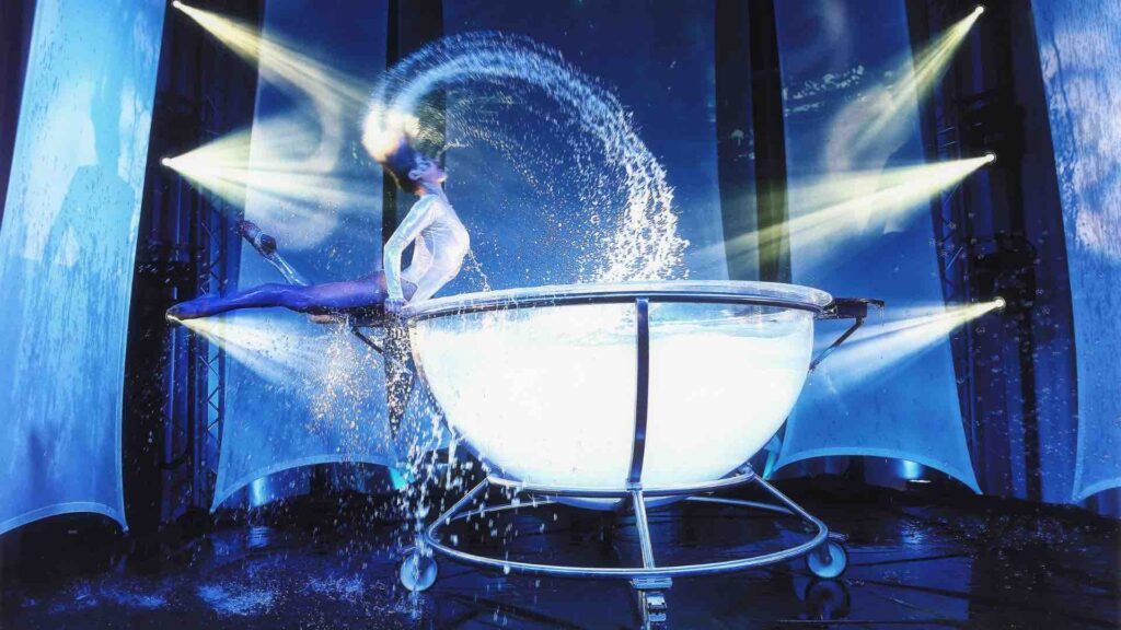 Lights shine on giant water bowl with acrobat