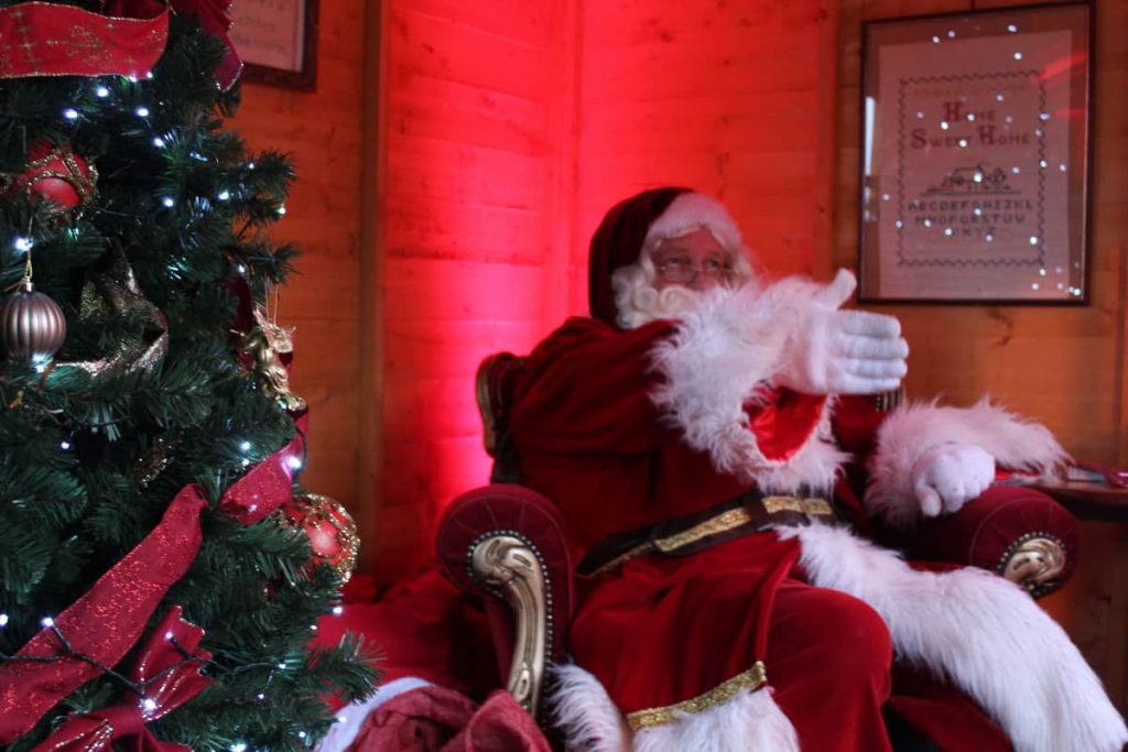 Santa Claus performer in a Father Christmas Chair next to a bespoke Christmas Tree inside our Santa Grotto. We fully produced and managed this newmarket Christmas event.