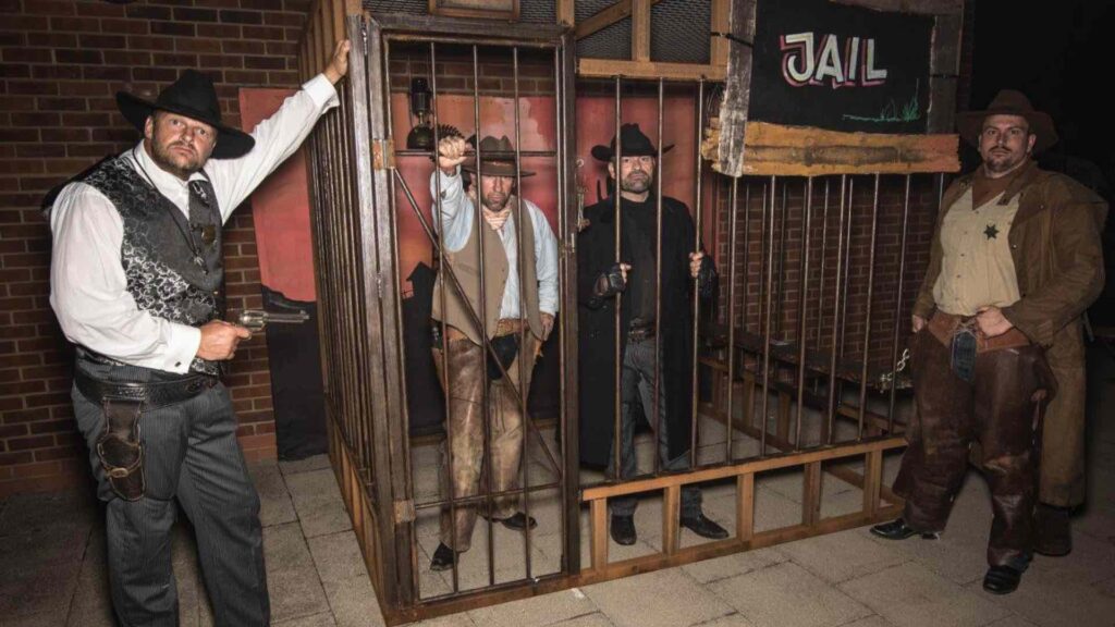 Jail set design with cowboys inside at a wild west themed event.
