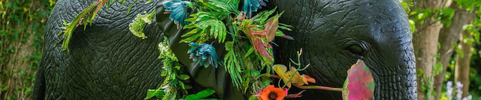 A giant elephant entangled in bright floral flowers used as event decoration.