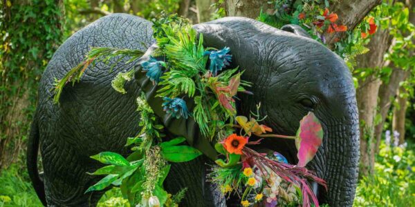 A giant elephant entangled in bright floral flowers used as event decoration.