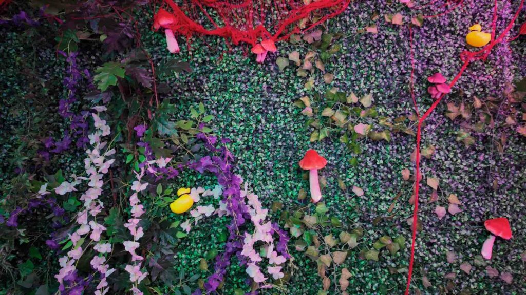 Flower and mushroom props with foliage decorating the interior of a jungle themed event.
