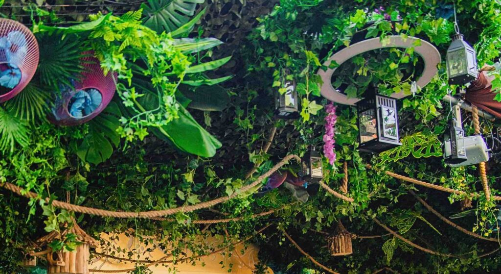 Hanging jungle event theme venue decorations including vines and flowers with ornaments.
