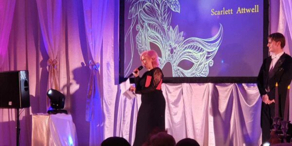 Speaker-On-Stage-At-Masquerade-Themed-Event