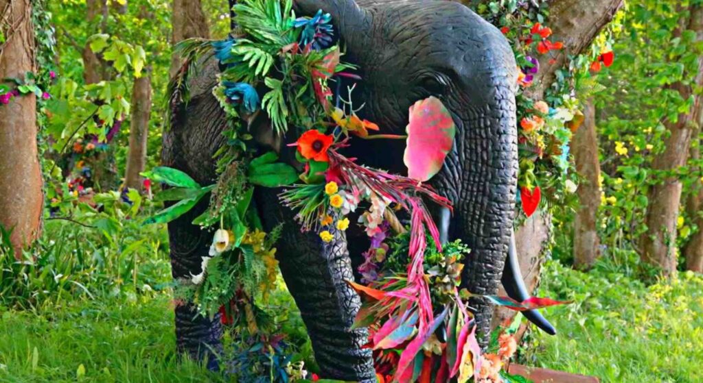 Giant elephant prop adorned with bright floral jungle flowers.