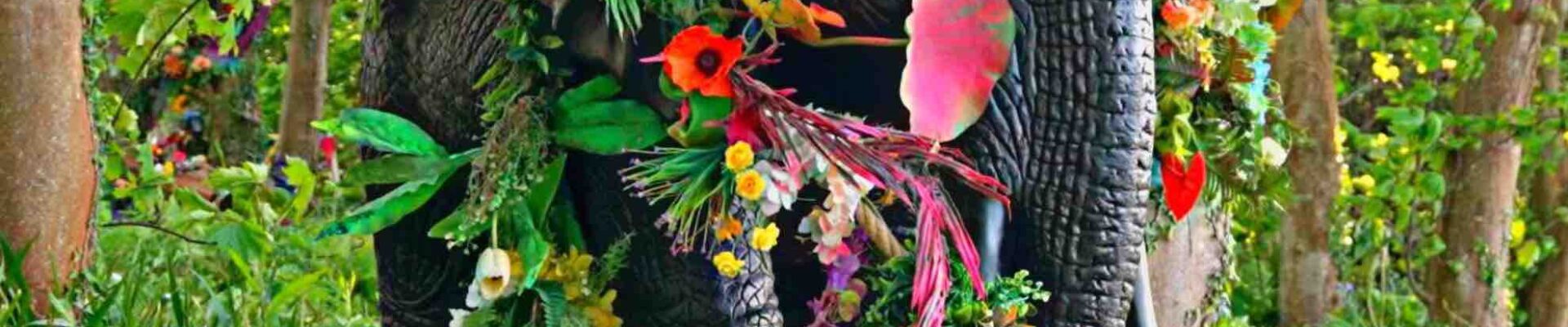 Giant elephant prop adorned with bright floral jungle flowers.