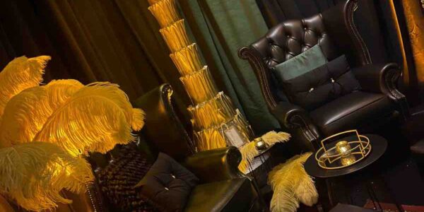 Giant 1920s style gold palm tree prop, leather armchair and ostrich feathers used to decorate 1920s themed room at event.