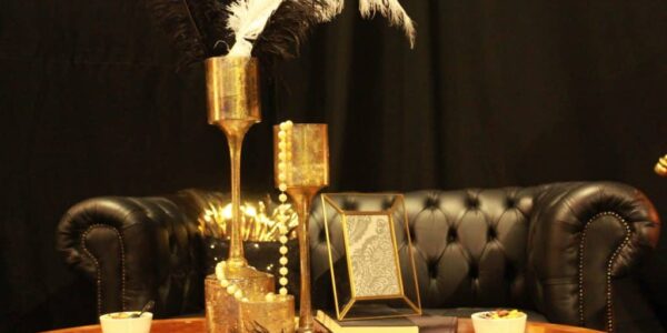 Gold accessories, pearl necklaces and ostrich feathers used to decorate table at 1920s themed event.
