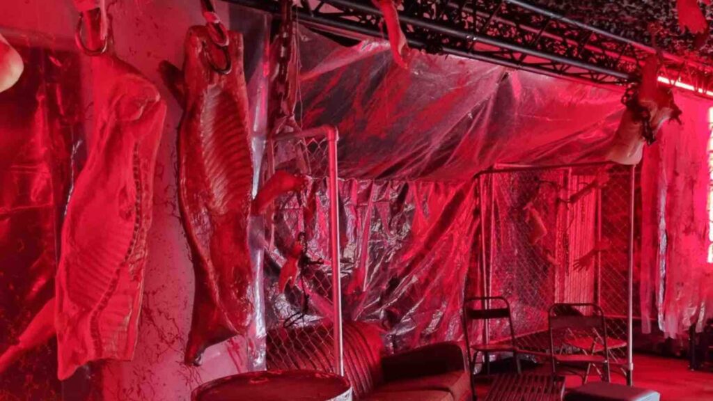 Dead animal part props hanging from the ceiling in slaughter house themed room at Halloween event