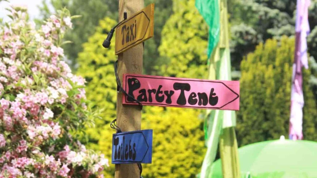 Wooden pole with signs attached to it to point guests in the direction of different areas at a festival themed event