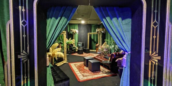1920s themed room with ornate gold frames, gramophone props, palm trees and vintage style rugs.