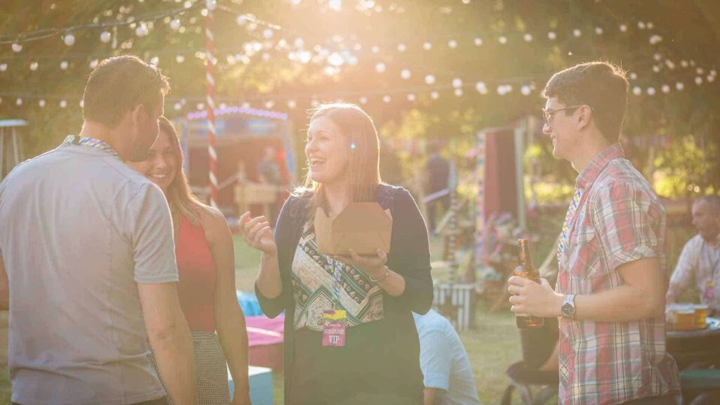 Guests at outdoor festival chatting with one another while eating.