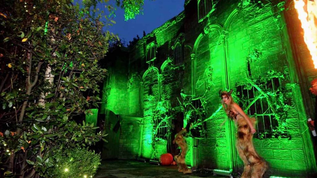 Outside of Halloween party venue dressed with cobwebs, green up-lighting, and Halloween entertainment.