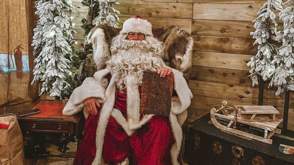 A classic father christmas posing in a cosy wooden santa's grotto