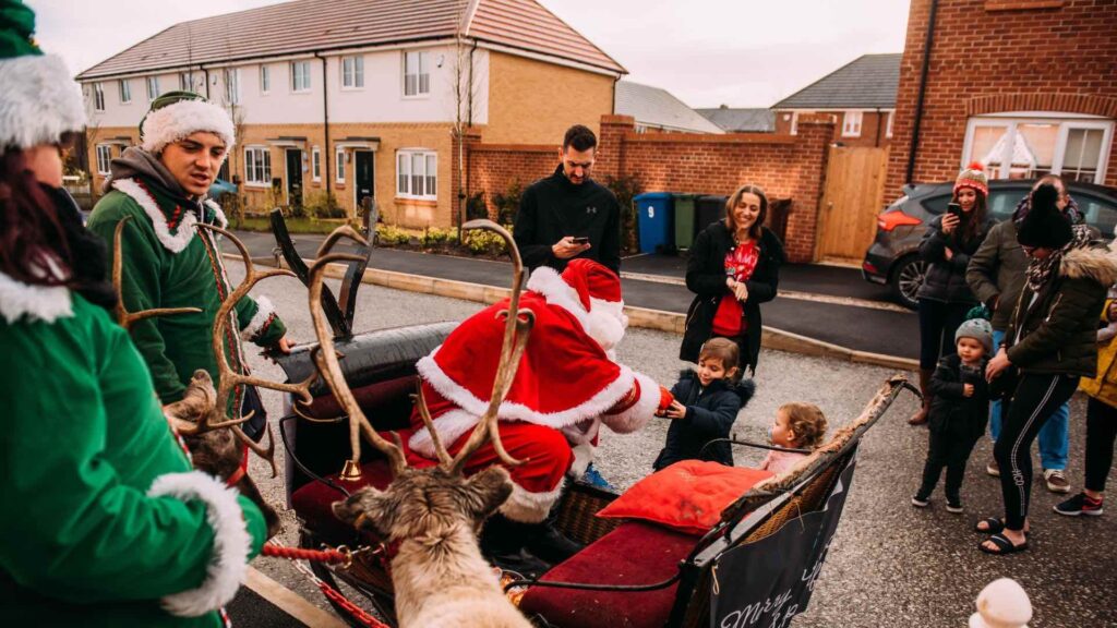 Santa Claus handing out presents to children on a public street