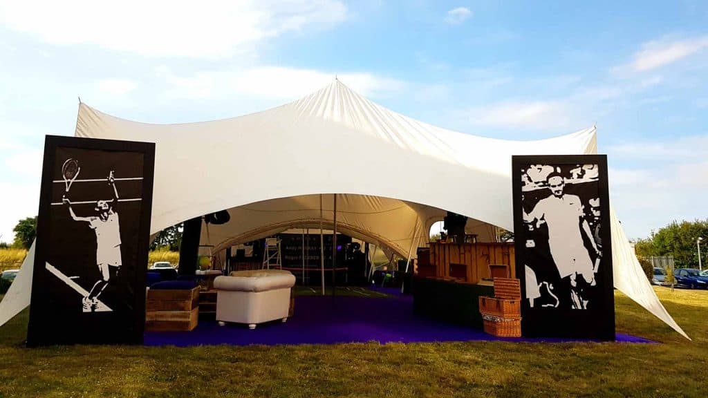 Tennis themed event production. Large white marquee with Wimbledon colour scheme decorations inside and Tennis star silhouettes.