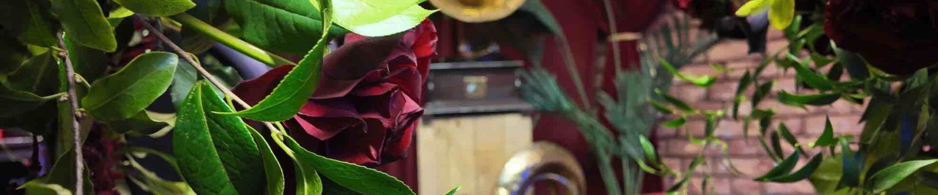 1920s themed musical event props installation including brass instruments and gramophone behind some flowers at a prohibition themed event.