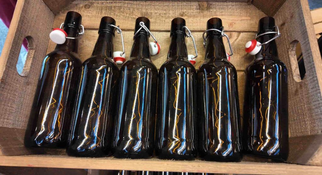 Brown alcohol bottles in a wooden crate used to theme a prohibition theme party.