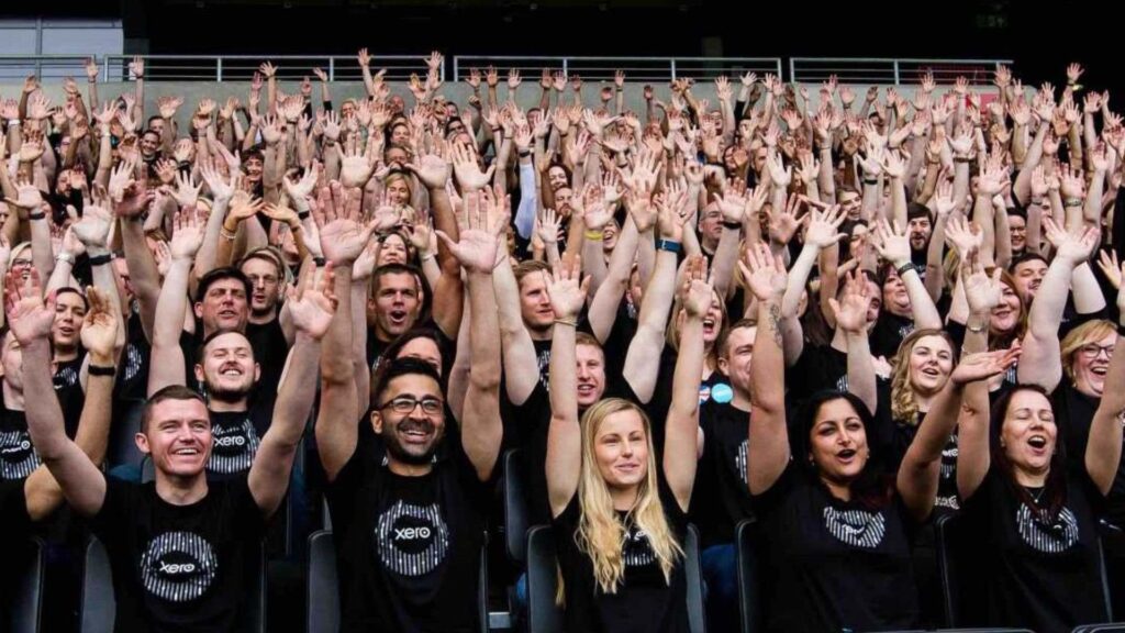 Group photo of delegates at conference with hands in the air.
