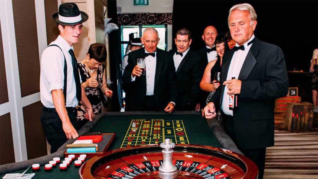 Men in tuxedos gathered round a roulette table hired for Las Vegas and Casino Themed Event