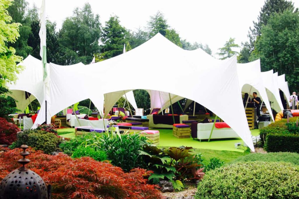 Festival party created in a back garden. Featuring a large white marquee and bright multi-coloured drapings.
