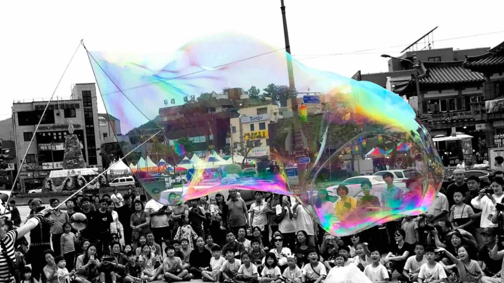 A giant bubble is created by a bubble performer at a festival in UK