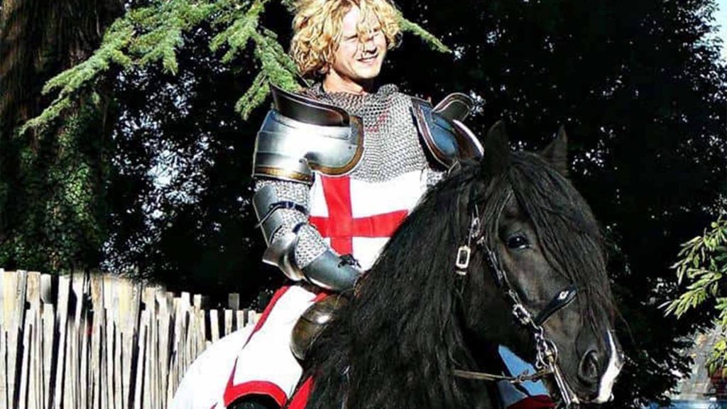 St.George with English flag on armour sat on large black horse. Available as part of medieval entertainment to hire London UK