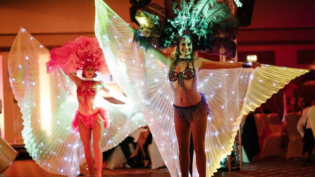 Vegas showgirls with light up wings performing in front of guests at Las Vegas Themed Gala Dinner. Available to hire London UK.