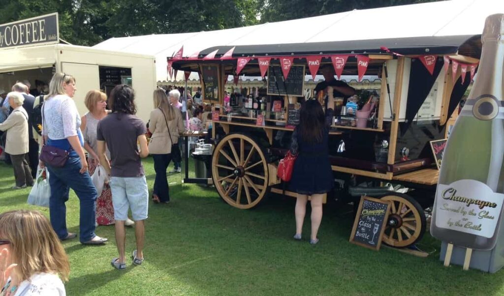 A crowd of guests getting food and drink at a Mobile Cocktail Bar