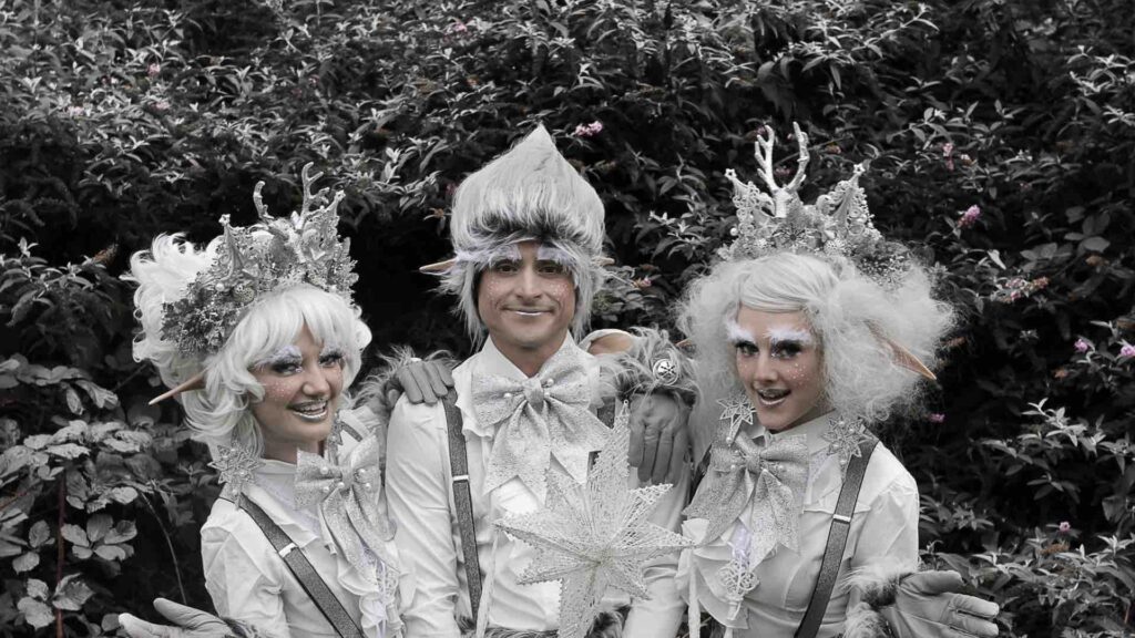 Trio of elves stood together posing for a photo, dressed in frosty white Winter attire