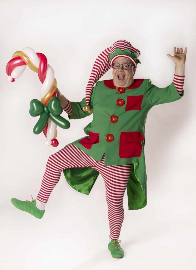 Christmas Elf Balloon Modeller with a Candy Cane created from green, white, gold and red balloons. This unique elf performer is available to book for Christmas Events across the UK and Worldwide.