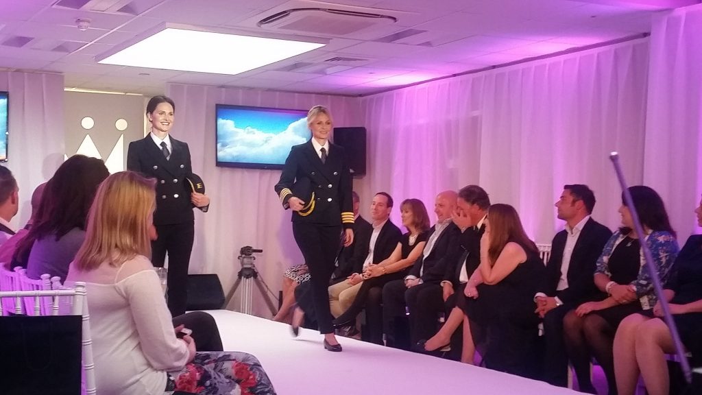 Monarch fashion show event we produce using our fashion show event production services. Two female models showcasing new pilot uniform down catwalk.
