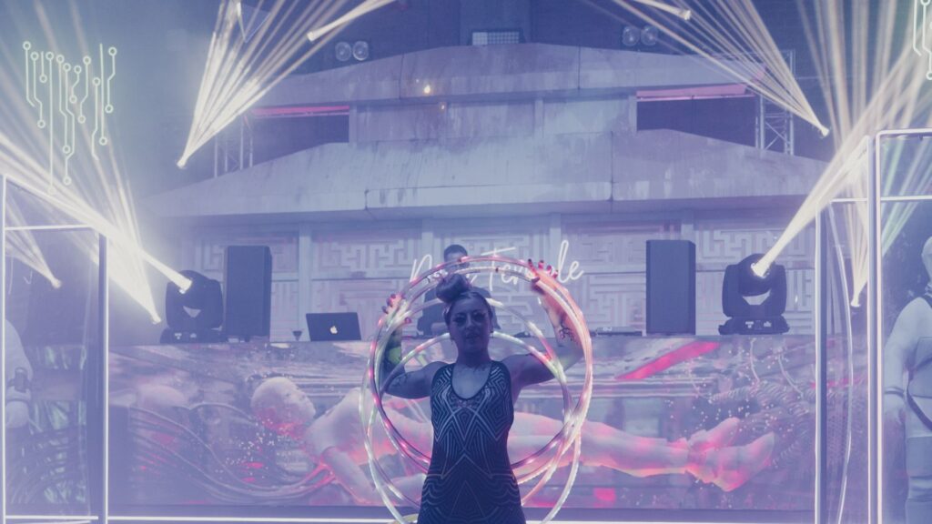 'Neon Temple' themed set and stage design with LED hoop performer standing in front of stage.