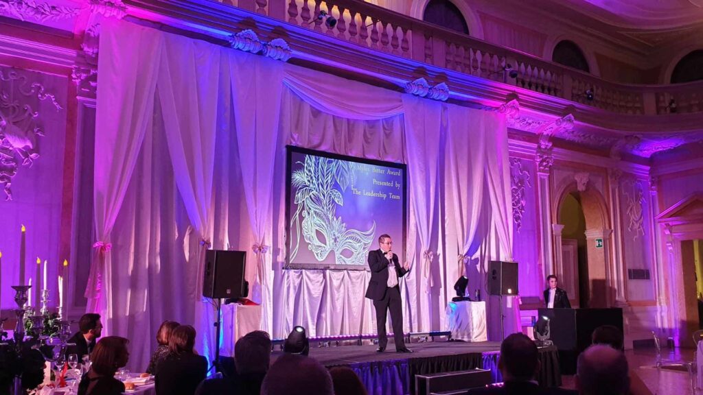 Guest speaker on stage at gala dinner event talking to audience.