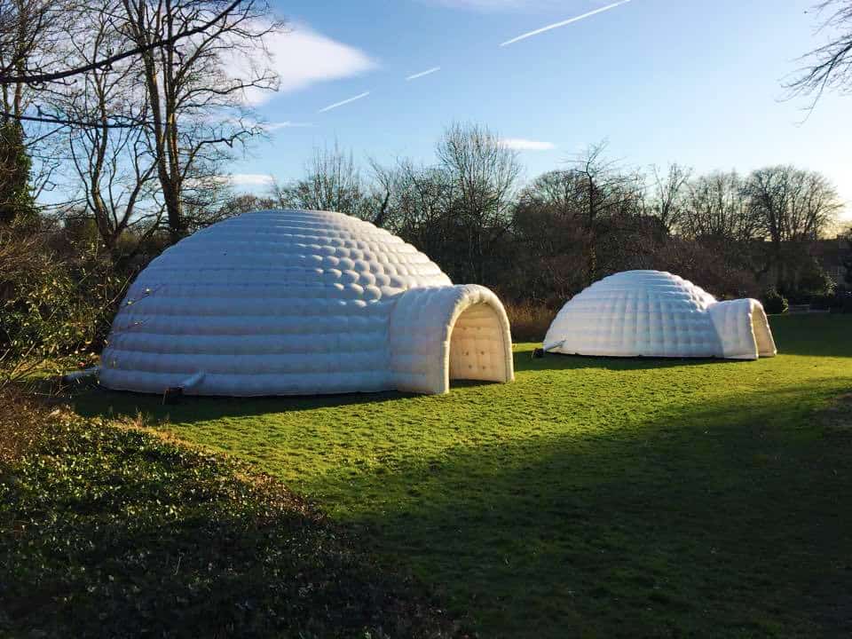 Two Large White Outdoor Inflatable Igloos next to each other outside.