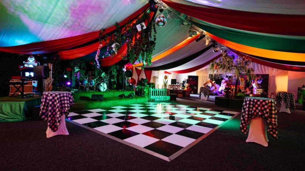 Alice in Wonderland Event Production inside draped marquee with projection lighting and checkered dance floor.