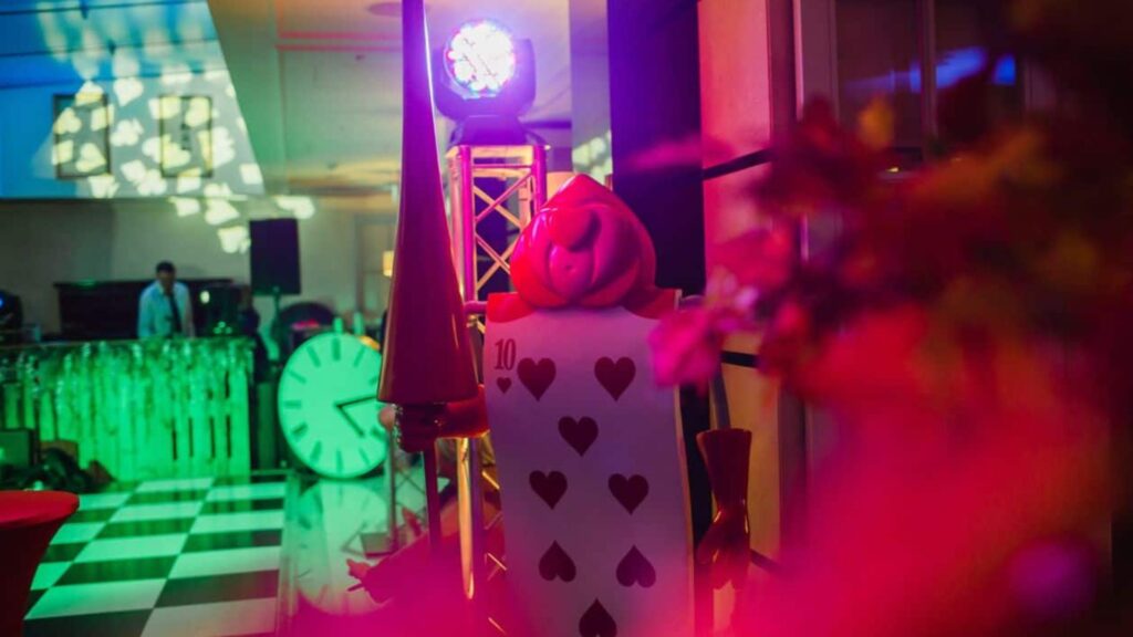 Alice in wonderland card prop in event space with green and pink projection lighting.