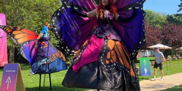 Butterfly stilt walkers engaging with guests during a lively corporate fun day event at Magna Carta Island, London.