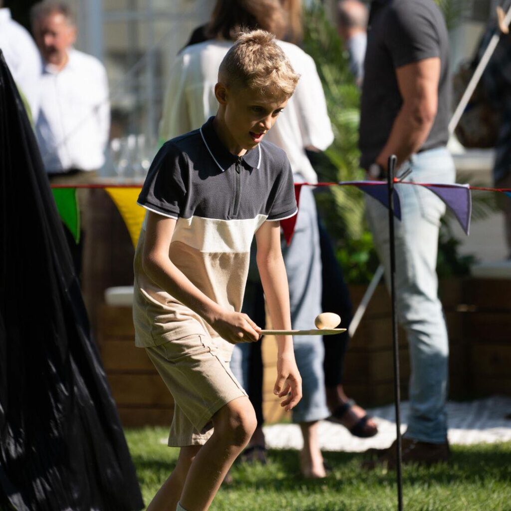 Egg and spoon race game being played by guest at outdoor event