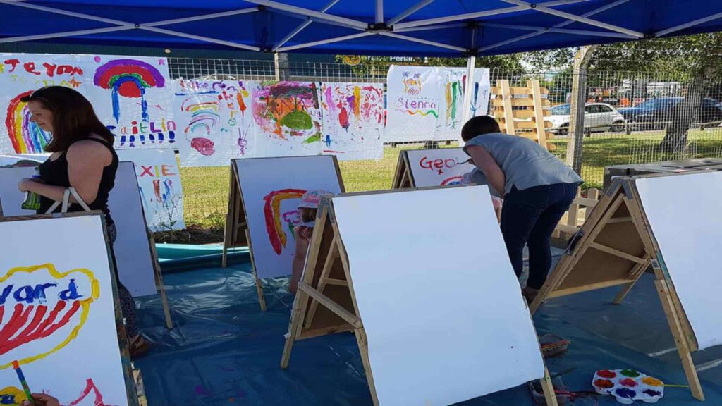 Paints and easels set up at arts and crafts station at family fun day event.