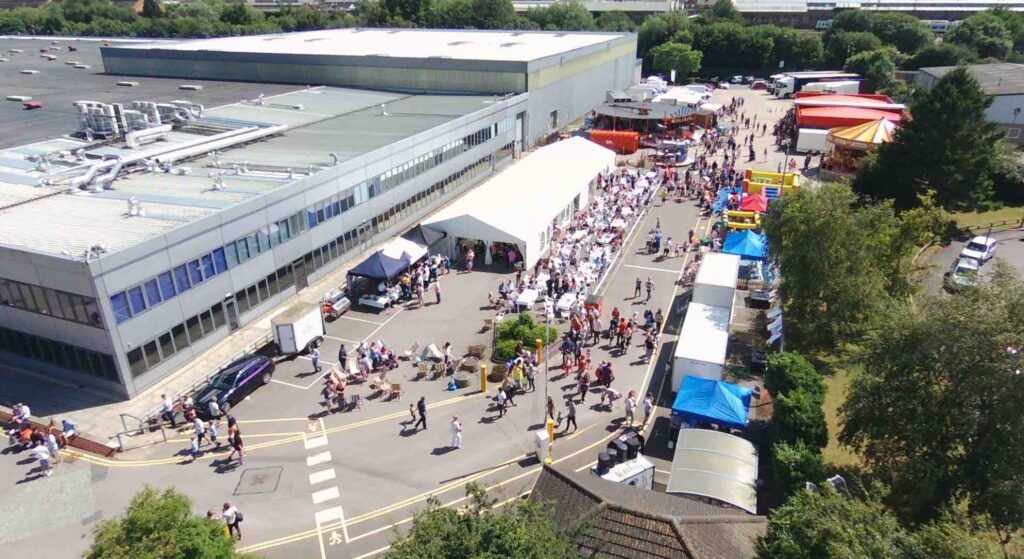 Corporate family fun day set up in a company car park with fairground attractions and stalls.