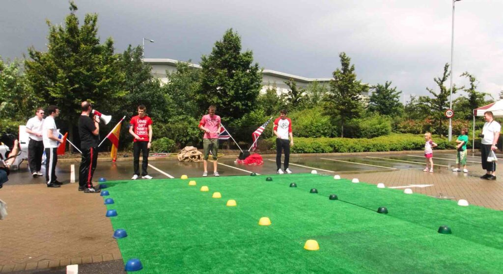 Corporate sports day with teams playing game on astroturf.
