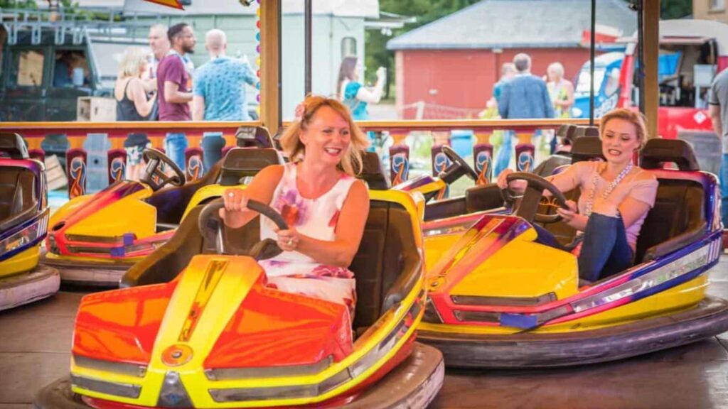 Two women racing each other in bumper cars at fairground themed event