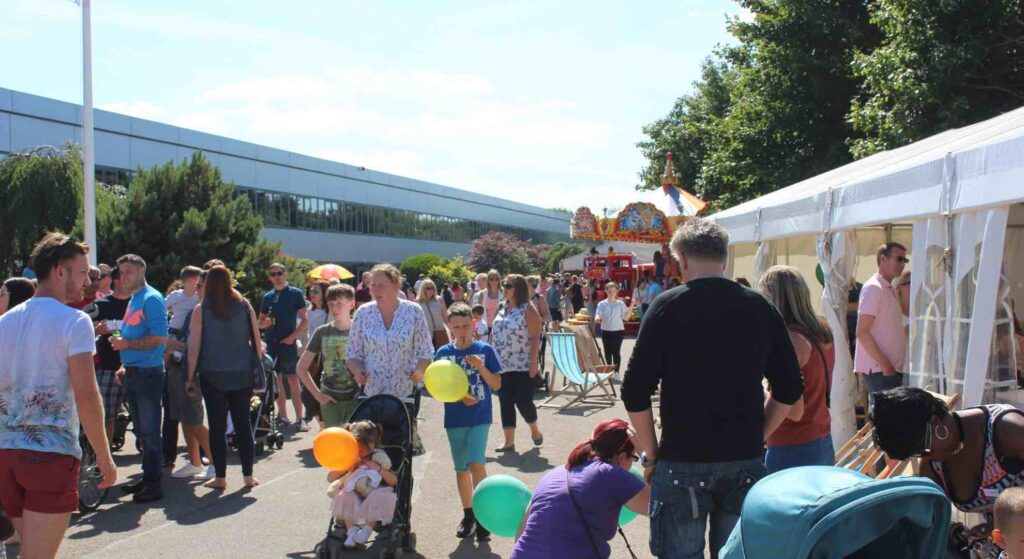 Families enjoying a corporate fun day in a car park.